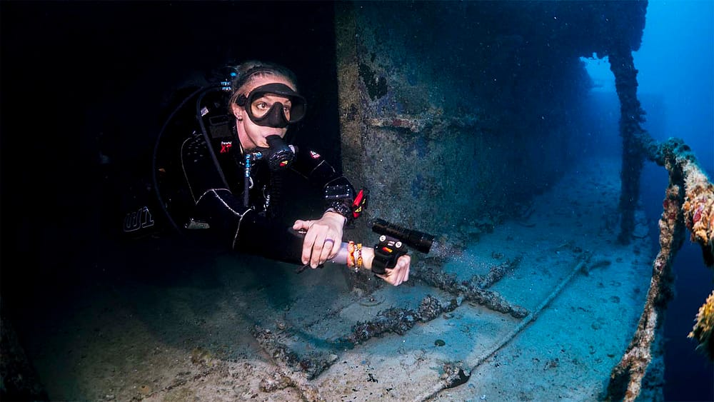 SDI Diver Explores Wreck with Flashlight
